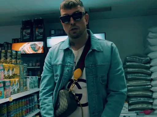 Malik Sentino w okularach i dżinsowej kurtce stoi w sklepie, otoczony towarem.
