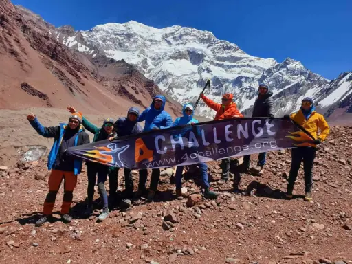 Grupa zdobywców z banerem "4 CHALLENGE" na tle majestatycznych gór z Aconcagua.