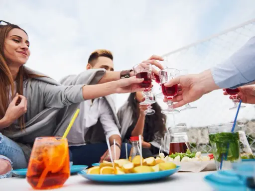 Grupa przyjaciół wznosi toast czerwonymi drinkami. Czy to już czas na digestif?