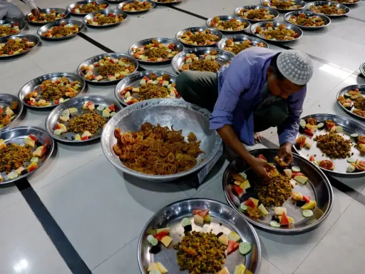 Männer bereiten Teller mit Essen und Obst für das Eid Fest vor.