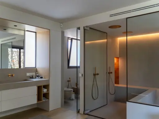 Moderno baño con ventana, ducha de cristal, bañera y lavabo doble.