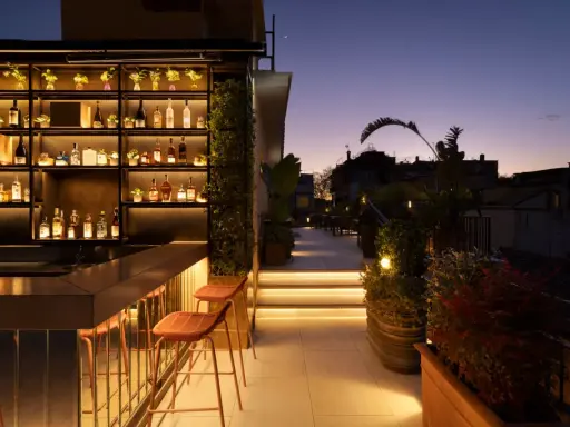 Terrazza panoramica con bar illuminato e sedie, ideale per scoprire le cose da fare a Roma nel weekend.