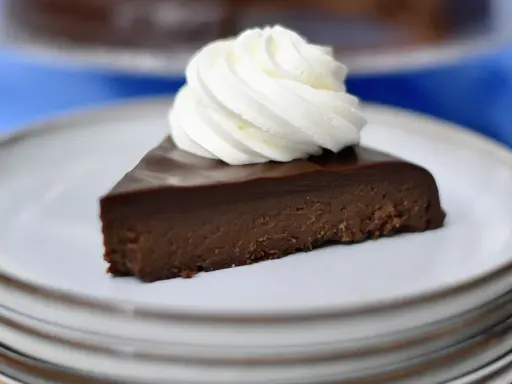 En bit fransk chokladtårta med en virvel av vispad grädde på en tallrik.