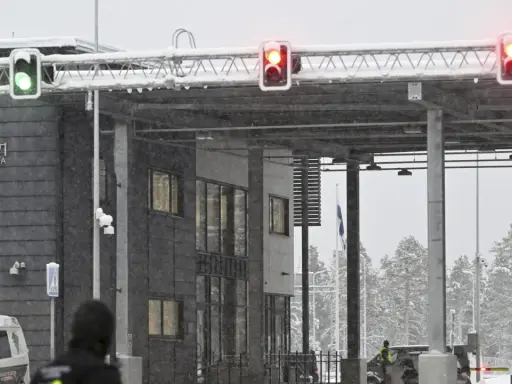 Grön trafiksignal vid gränsövergången Joensuu, Finland. Snö faller över byggnaden och träden. En polisbil syns. Gränsen mellan Ryssland och Finland är stängd.
