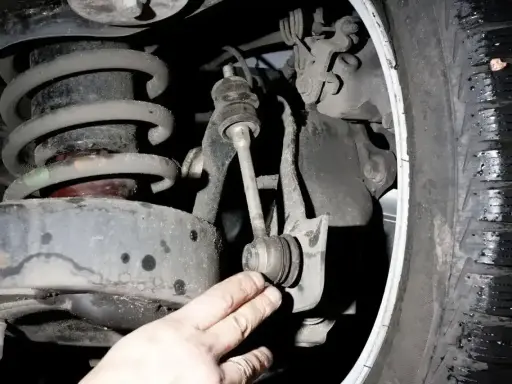 Uszkodzony łącznik stabilizatora objawy: stukanie, luzy w zawieszeniu. Widoczny element zawieszenia samochodu.