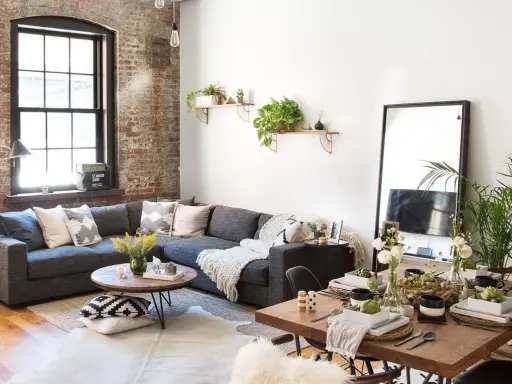 Sofá gris, mesa de centro redonda, mesa de comedor de madera y espejo de cuerpo entero crean un ambiente de **estilo cozy**.