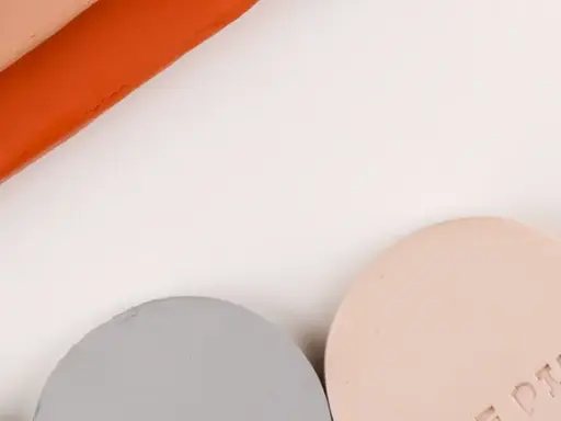 Stavar av lera som inte torkar i grått, rosa och orange, samt runda provbitar märkta "TERRACOTTA" och "ROSE PINK".