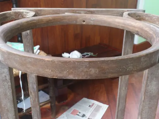 Estructura de madera de un palanganero antiguo, lista para restaurar. Se aprecian sus patas y el aro superior curvo.