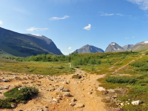 Vandringsled mot Kebnekaise, en fantastisk utsikt som gör bestiga Kebnekaise pris värt. Berg, grönska och en klarblå himmel.