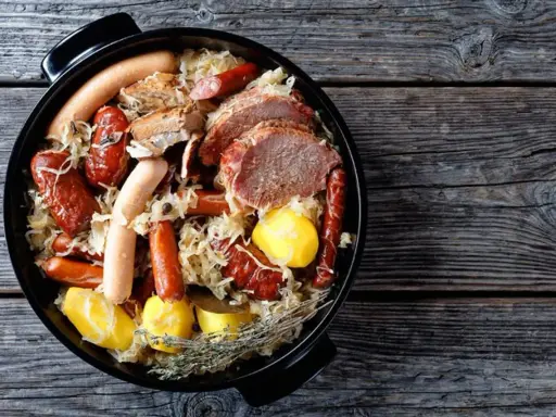 Choucroute garnie, un plat emblématique des alsace spécialités culinaires, avec saucisses, viandes et pommes de terre dans une cocotte.