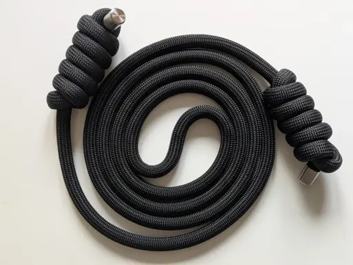 Schwarzes Seil mit Metallenden, kunstvoll zu einer Spirale gewickelt. Der rope flow erzeugt ein faszinierendes Muster.