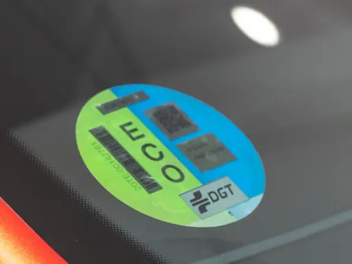 Mini etiqueta eco en parabrisas. Muestra el distintivo DGT y códigos QR para identificar vehículos de bajas emisiones.