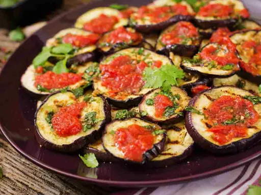 Fette di melanzane grigliate condite con salsa di pomodoro e basilico, un gustoso piatto di melanzane alla pizzaiola.