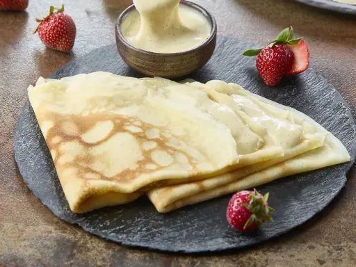 Délicieuses crêpes de riz garnies de crème vanillée, accompagnées de fraises fraîches. Un délice gourmand.