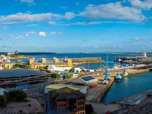 Vista panoramica del **southampton porto** con navi, gru e edifici moderni sotto un cielo azzurro con nuvole bianche.