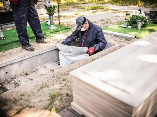 Pracownicy przygotowują ekshumację po 30 latach. Widać trumnę i koparkę.