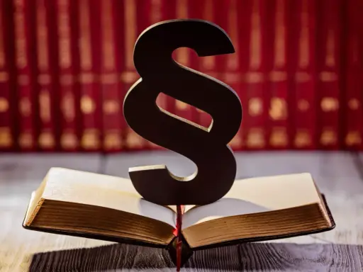 Symbol paragrafu na otwartej księdze, sugerujący karę finansową dla pracownika. W tle rząd czerwonych ksiąg.