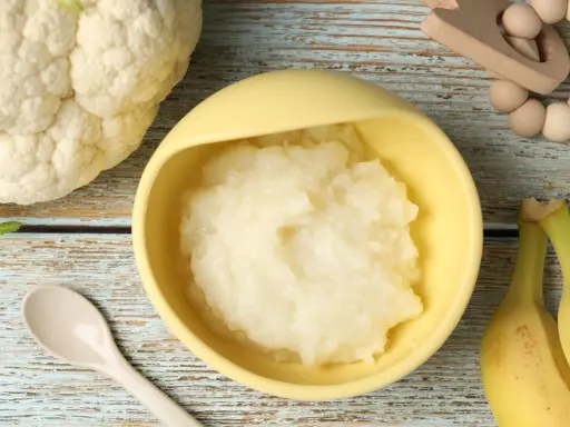 Puré de coliflor listo para servir. Ideas de recetas de coliflor para niños, con plátanos y cuchara.
