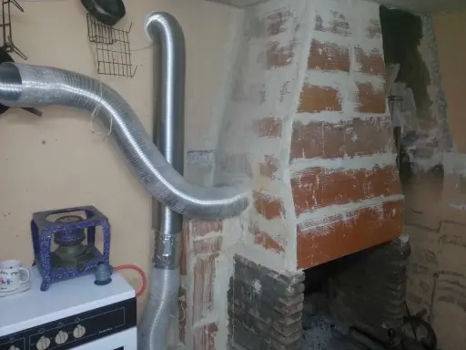 Instalación de tubos flexibles para estufa de leña, conectando a la chimenea de ladrillo.