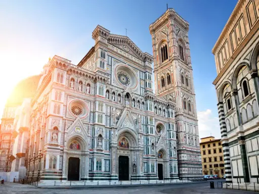 La majestueuse coupole de Florence, le Duomo, se dresse fièrement sous un ciel bleu, baignée par les rayons du soleil.