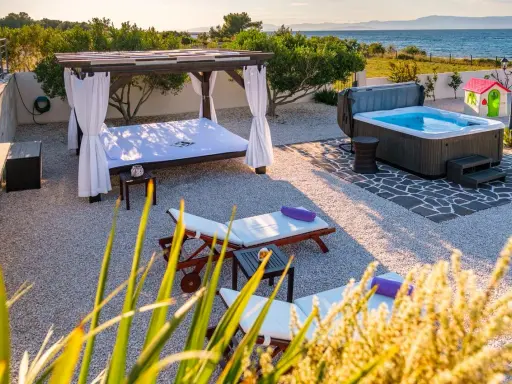 Relaks przy morzu: leżaki, jacuzzi i baldachim w chorwackim apartamencie.