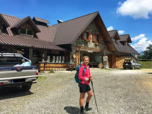 Ragazza con zaino e bastoncini da trekking davanti alla malga Lavareit, con un pick-up e un'auto parcheggiati.