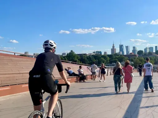 Rowerzysta na moście w Warszawie, w tle panorama miasta. Idealne miejsce na odkrywanie tras rowerowych Warszawa i okolice.