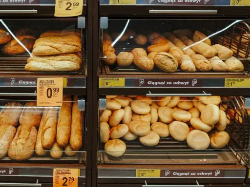 Różnorodne bułki i bagietki na półkach sklepowych. Idealne na śniadanie, choć warto sprawdzić ich kcal.