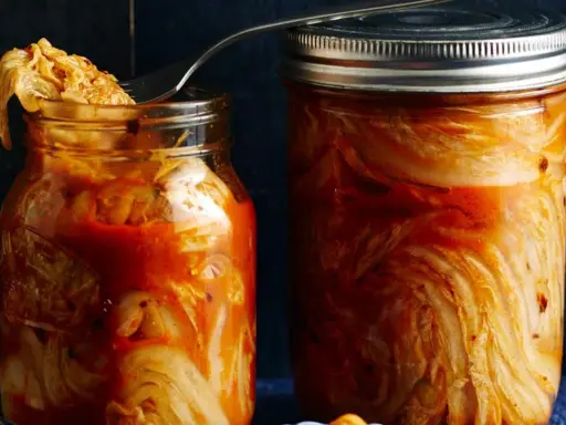 Zwei Gläser mit fermentiertem Chinakohl, bereit für das authentische kimchi rezept original. Ein Löffel ragt aus dem linken Glas.