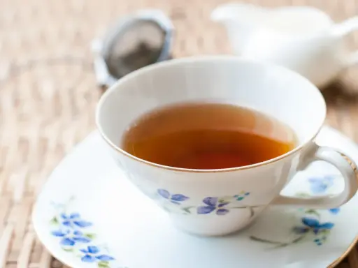Aromaticzna herbata Earl Grey, znana ze swoich właściwości pobudzających i relaksujących, w eleganckiej filiżance z niebieskimi kwiatami.