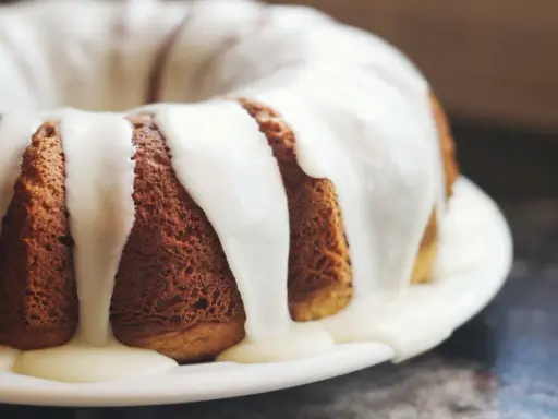 Gâteau moulé, doré, nappé d'un glaçage blanc crémeux. Une invitation à découvrir comment faire du fondant blanc.