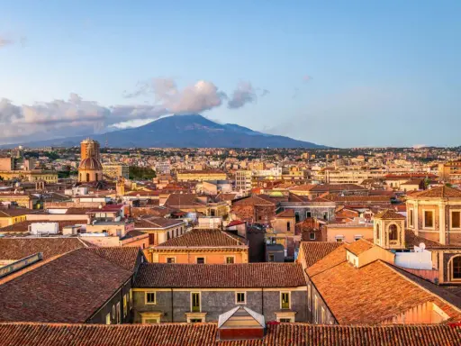 Vista panoramica di Catania con l'Etna sullo sfondo. Tetti rossi, cupole e palazzi storici offrono spunti per le cose da fare a Catania.