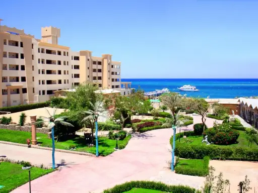 Piękny widok na **King Tut Resort** z basenem, palmami i morzem w tle.
