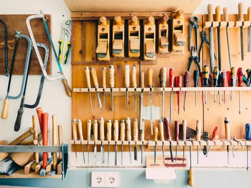 Un bel aménagement atelier avec des rabots, des scies, des tournevis et d'autres outils de menuiserie bien rangés sur un panneau en bois.