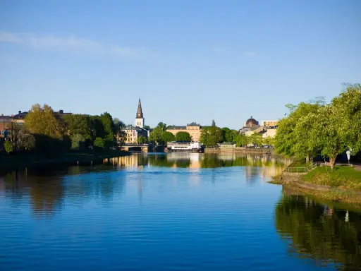 Vacker stad vid vattnet med kyrktorn och gröna träd. Tänk dig att bo på ett mysigt vandrarhem i Torsby och vakna till denna vy.