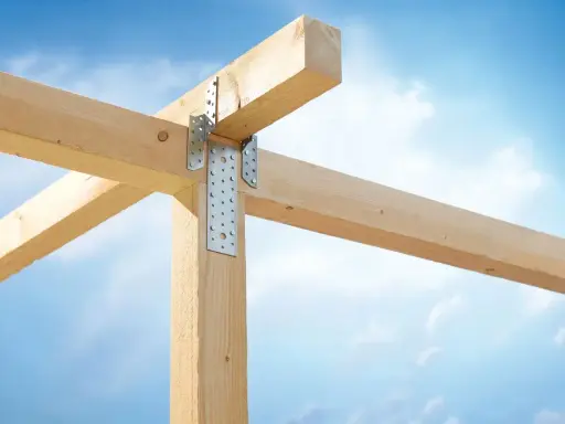 Stabile Holzverbindungen mit Metallwinkeln sichern die Balkenkonstruktion gegen den blauen Himmel.