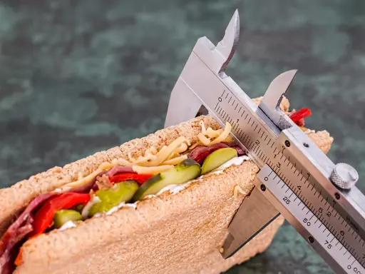 Kanapka z serem, mięsem i warzywami, mierzona suwmiarką. Wygląda na to, że ma duzo kcal.