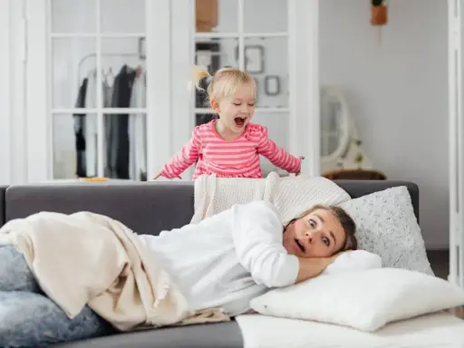 Niña emocionada sobre el sofá, mientras su madre se asusta. ¡Un día típico con el horario para niños en casa!
