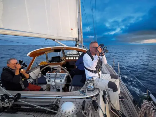 Leon Schulz und ein Kollege filmen auf See. Die Segel sind gesetzt, die Wellen schlagen gegen das Boot.