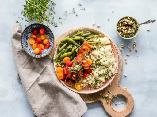 Un délicieux repas parisien : saumon grillé, haricots verts, riz et tomates cerises, accompagné de pesto et de pousses fraîches.