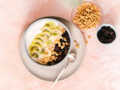 Gesunder Joghurt-Bowl mit Kiwi, Beeren, Nüssen und Granola – perfekt für proteinreiche Mahlzeiten.