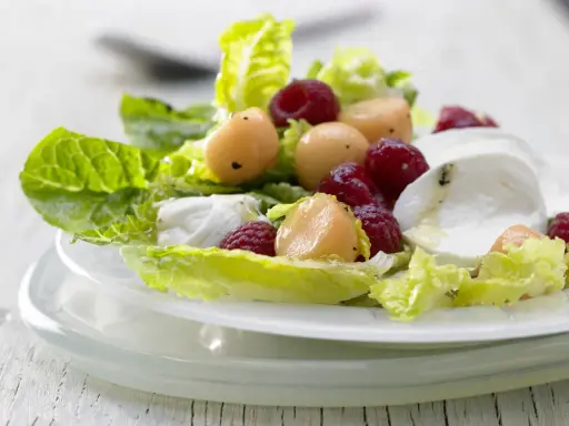 Erfrischender melonensalat mit mozzarella, Himbeeren und knackigem Salat. Ein leichter Genuss für warme Tage.