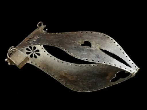 Metalowy pas cnoty, ozdobiony kwiatami i sercem, z ząbkowanym zamknięciem.