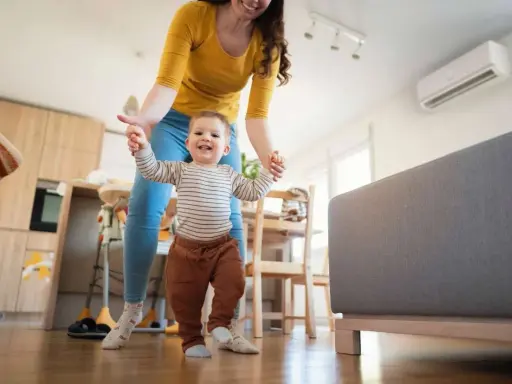 Mamma aiuta il suo bambino a fare i primi passi, con l'aria condizionata neonati che garantisce un clima ideale in casa.