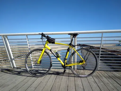 Bicicletta gialla pronta per un giro a Rimini Cattolica, con il mare e la spiaggia sullo sfondo.