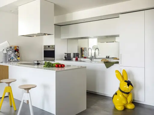 Cucina moderna con isola centrale e sgabelli. La differenza tra RAL 9003 e 9010 è sottile, ma qui il bianco puro domina, con un tocco di giallo dato da un coniglio decorativo.