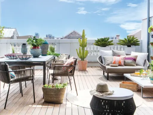 Ideas para decorar una terraza: mesa, sillas, sofá, plantas y cestas crean un espacio acogedor y moderno.