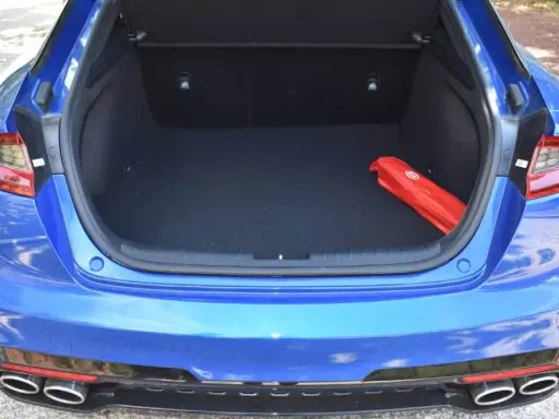Maletero abierto de un Kia Stinger azul, con un botiquín rojo en el interior.