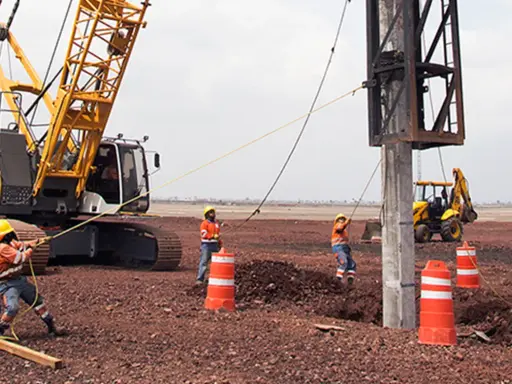 Trabajadores y maquinaria pesada instalan pilotes para cimentaciones profundas en un sitio de construcción.
