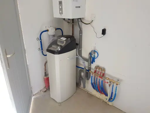 Installation d'un adoucisseur d'eau Comap, avec chaudière et tuyauterie. Un problème potentiel avec l'adoucisseur Comap est visible.